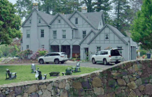 A large house with many cars parked in front of it.