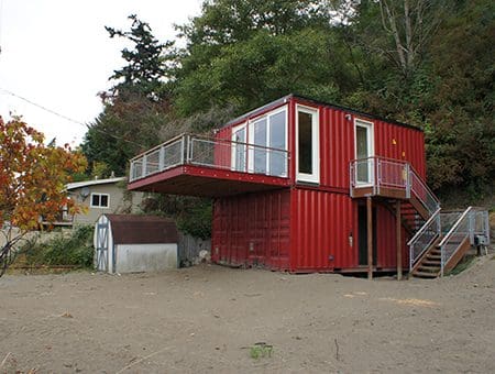 A red container house with stairs leading to the top.